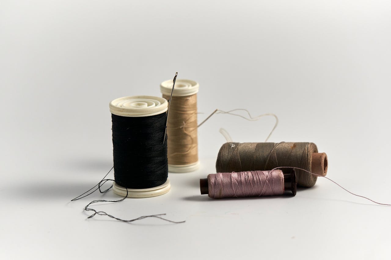 Close-up of colorful sewing threads and needles on white background.