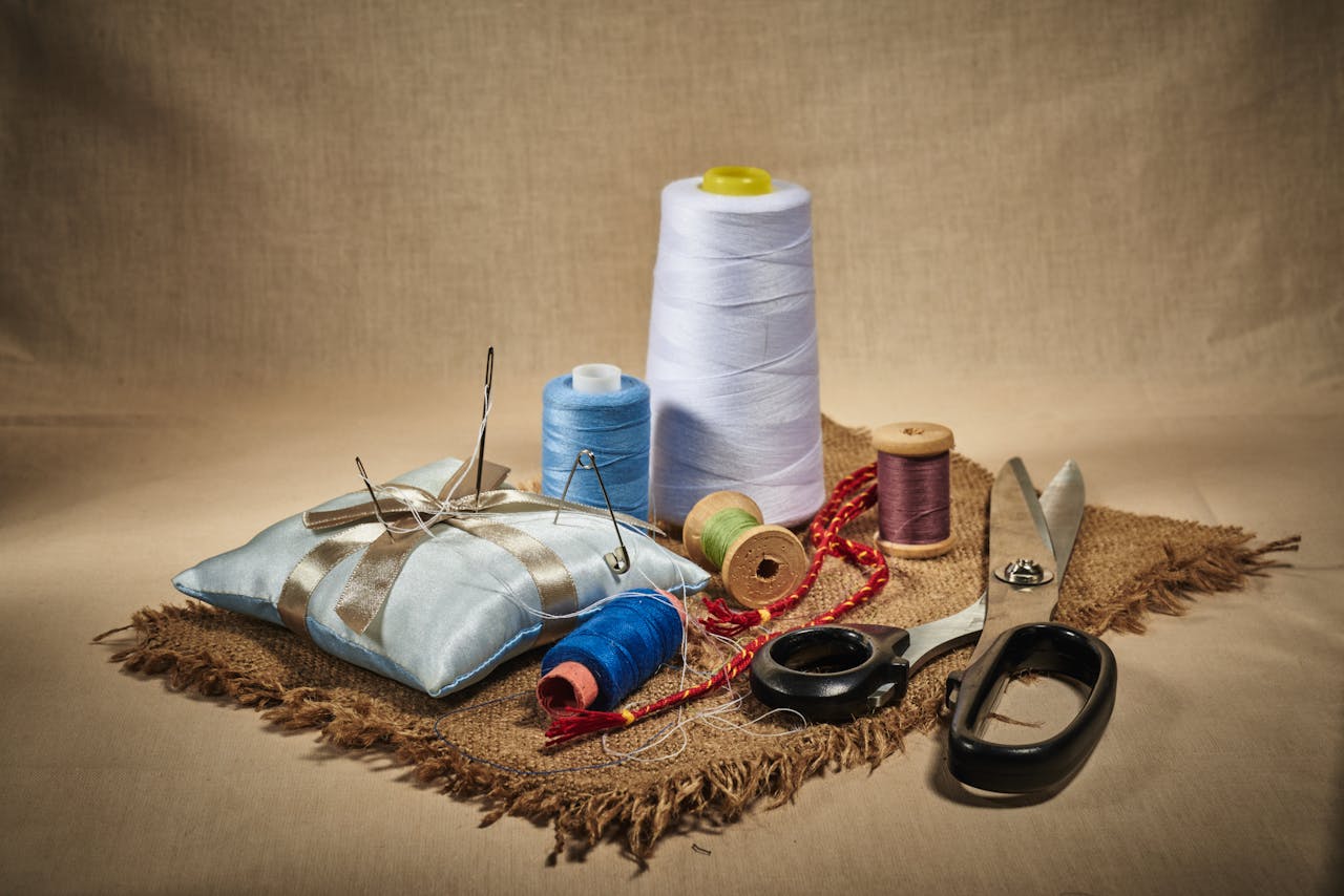 A vibrant display of sewing tools including threads, scissors, and needles on a burlap cloth.