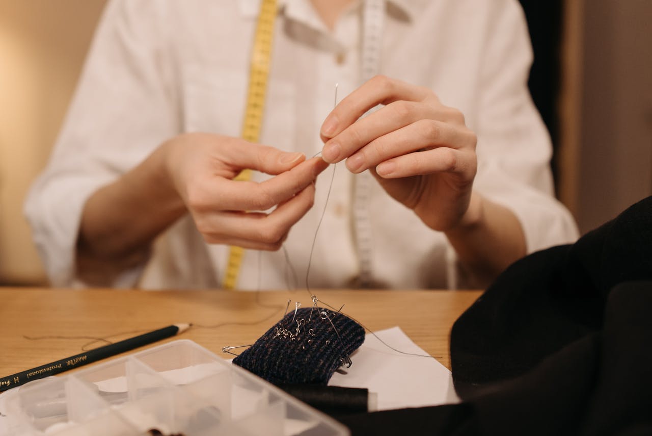Detailed view of hands sewing fabric with needle and thread, capturing the art of tailoring.
